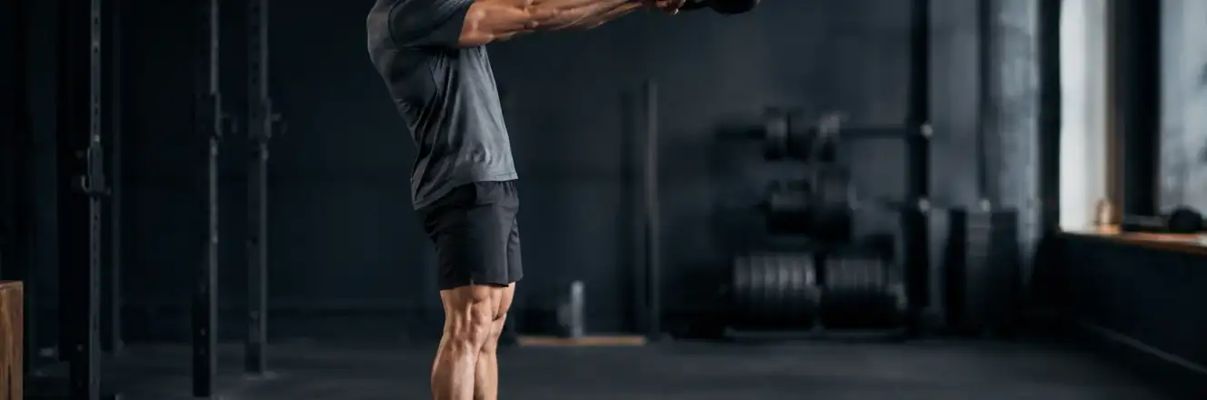 Person i toppen af et kettlebell swing med hoften strakt og vægten i brysthøjde